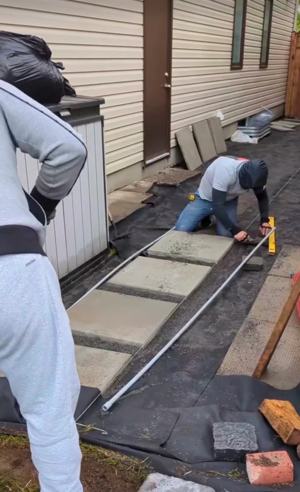Adel's Yard Services crew installing custom stone paver walkway with level line and gravel base