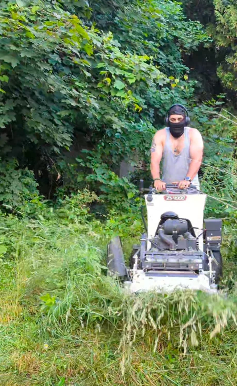 Adel operating a commercial stand-on brush mower clearing tall grass and heavy overgrowth